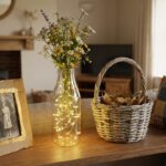 Home shelf with upcycled decor items including bottle vase with fairy lights newspaper basket painted cardboard frame and fabric cushion covers