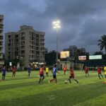 Floodlit artificial turf sports ground in Navi Mumbai with players during an evening football match