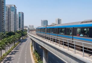Navi Mumbai Metro train on elevated viaduct passing through modern city with palm trees and residential towers