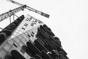 Old residential building beside a new high-rise under construction with crane, illustrating society redevelopment in Navi Mumbai