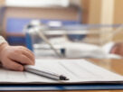 A newborn baby's hand resting on a document with a pen