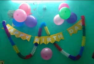 Yellow HAPPY BIRTHDAY bunting with pink, green and purple balloons on a wall; illustrative party decoration, not a specific Navi Mumbai venue