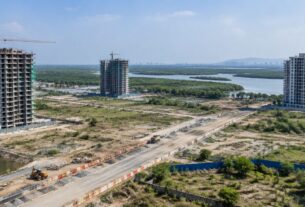 Illustrative AI-generated view of under-construction towers near a creek and mangroves, not an actual Dronagiri location.