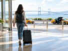 Illustrative AI-generated scene of a traveller with luggage beside airport taxis.