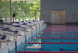 Empty indoor swimming pool with lane ropes and starting blocks, illustrative image not depicting a specific Navi Mumbai venue