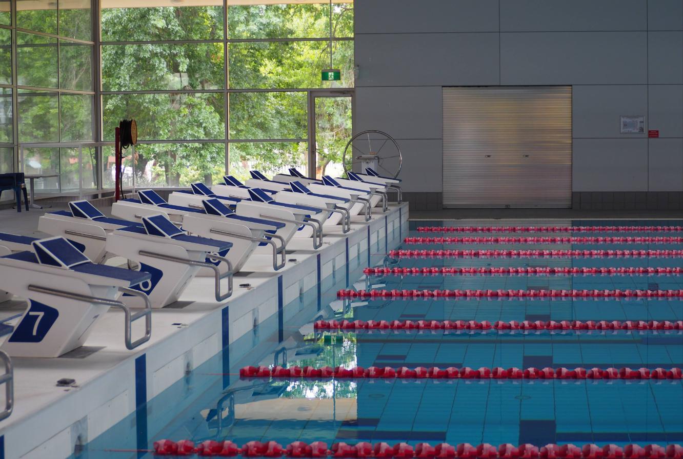 Empty indoor swimming pool with lane ropes and starting blocks, illustrative image not depicting a specific Navi Mumbai venue