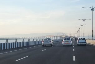 Cars driving on the Atal Setu sea bridge in Mumbai, with the long bridge and street lights ahead