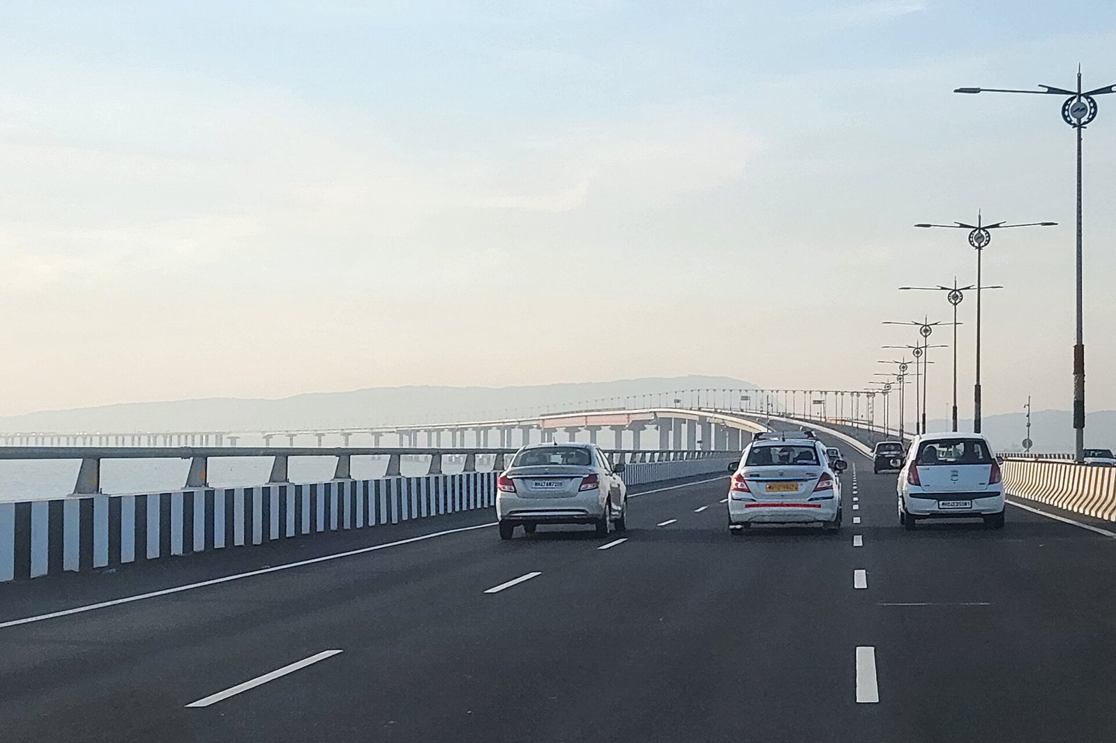 Cars driving on the Atal Setu sea bridge in Mumbai, with the long bridge and street lights ahead