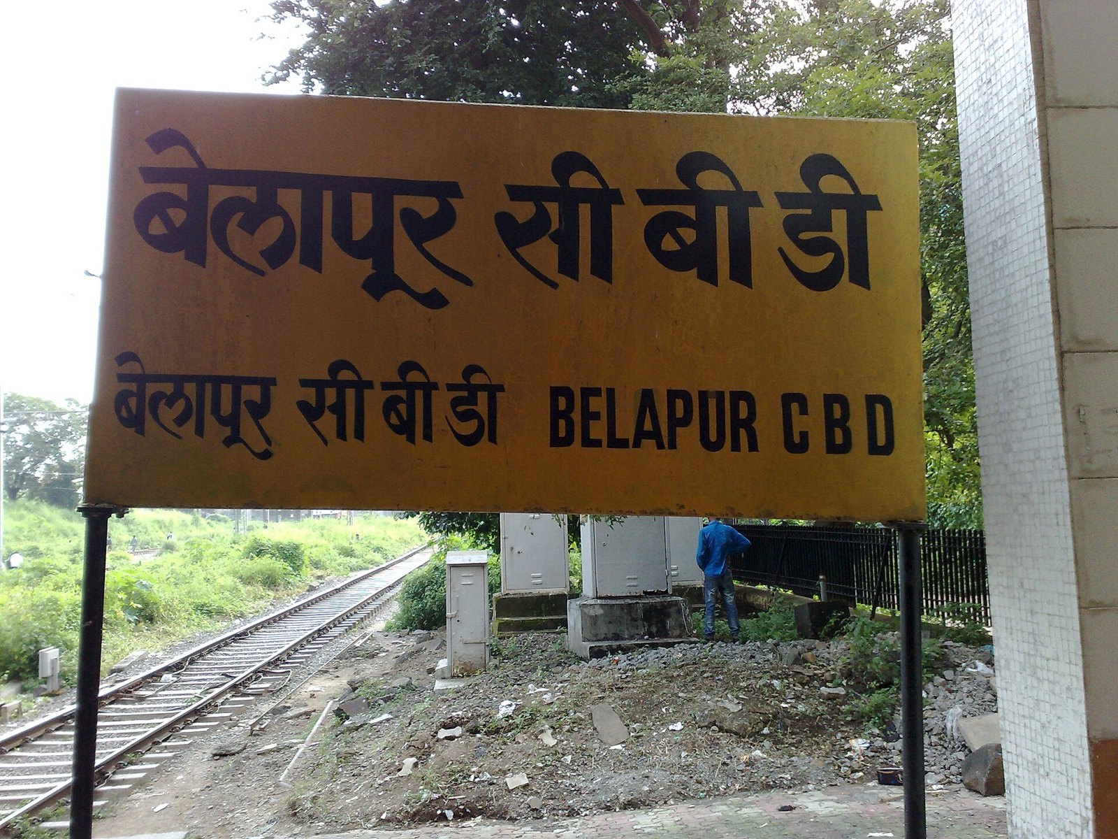 Belapur CBD station name board in Hindi and English beside the railway track