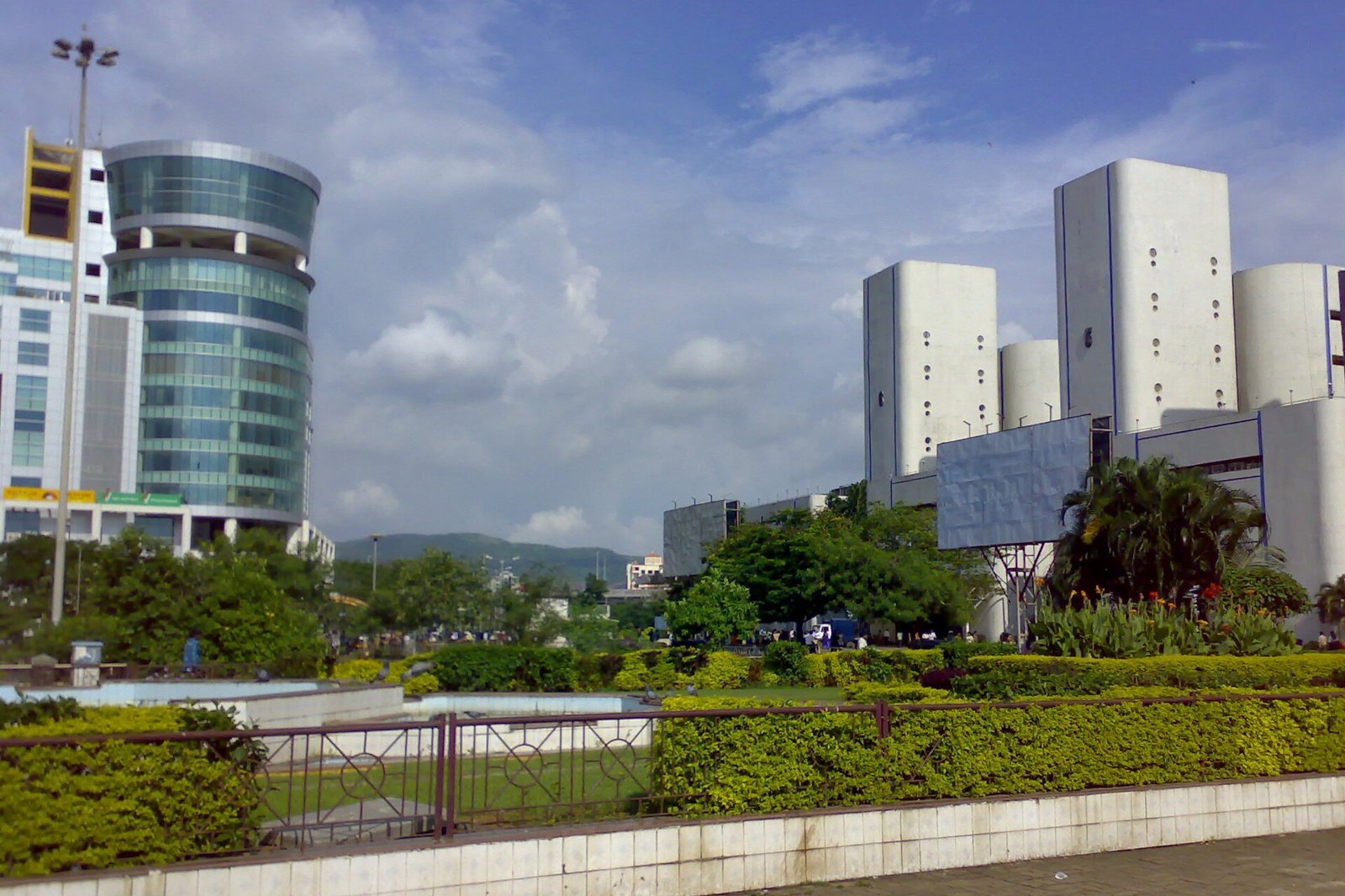 Glass and concrete office towers beside landscaped gardens under a blue sky in Navi Mumbai