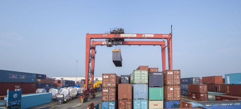 Home 6 A gantry crane lifting a container in a stacked container yard near JNPT