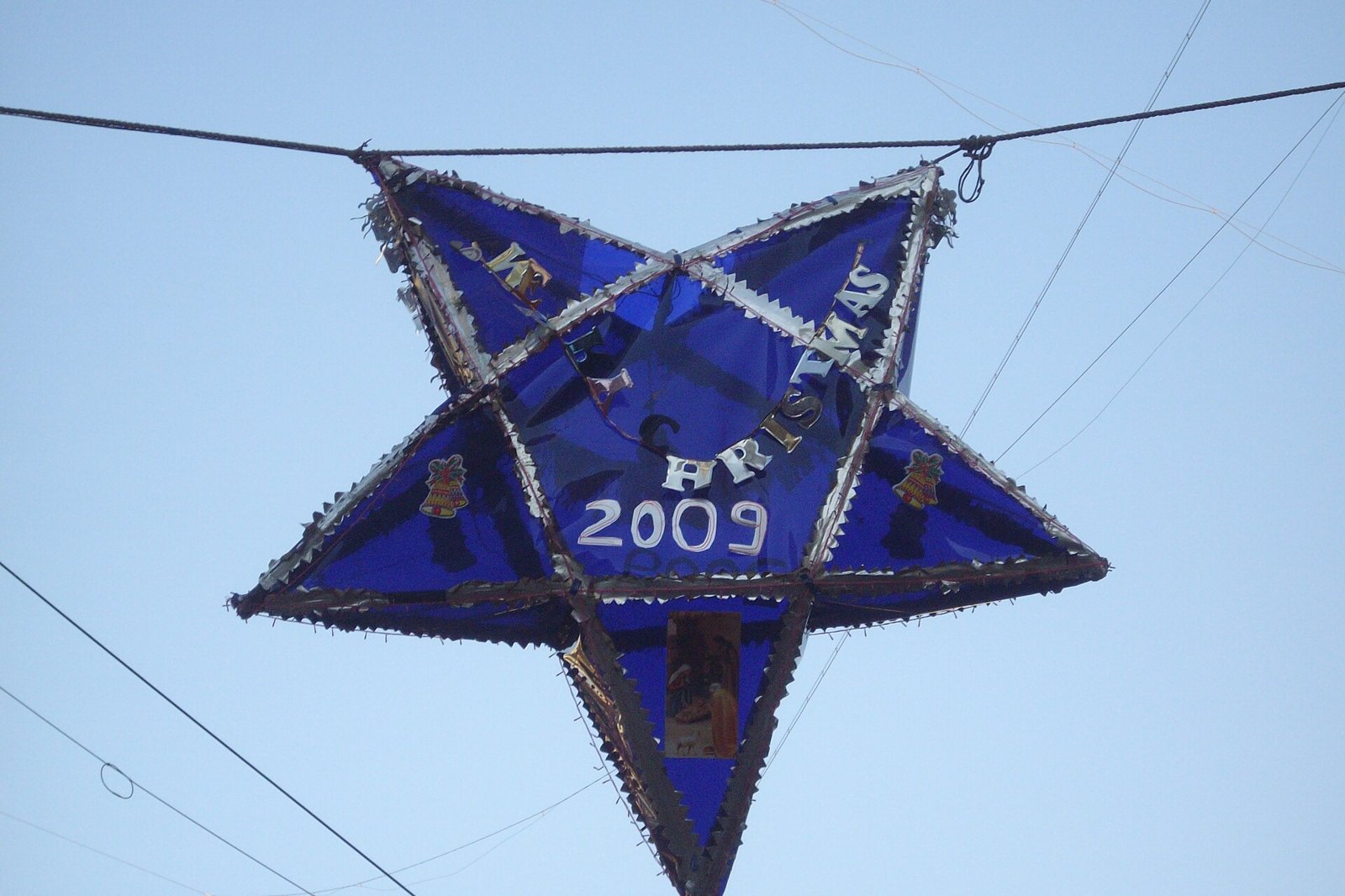 A blue star shaped Christmas lantern hanging from a wire against a pale sky in Mumbai