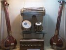 Two tanpuras, a pakhawaj, a pair of tabla and a harmonium displayed in a glass case in a Pune museum