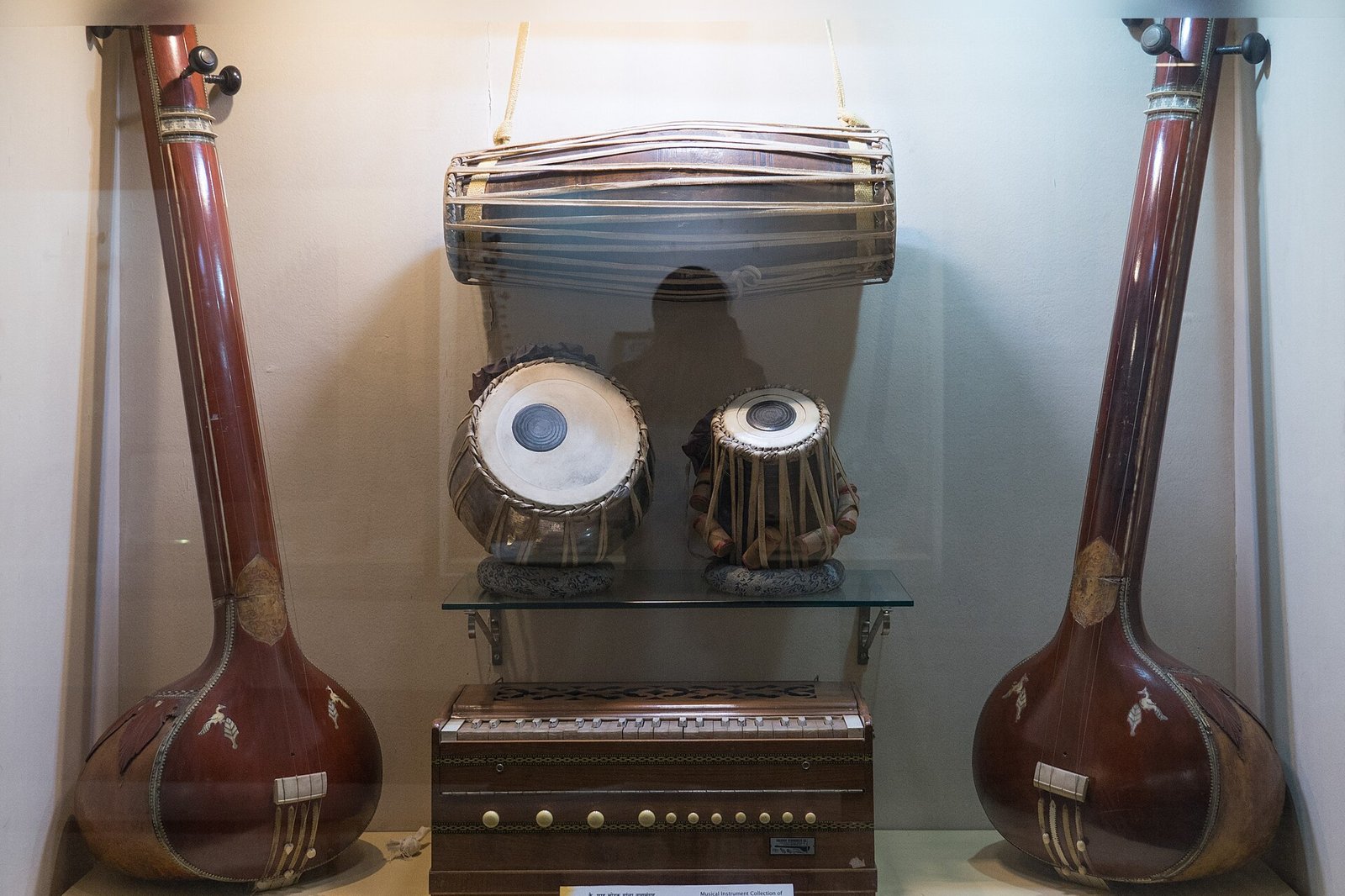 Two tanpuras, a pakhawaj, a pair of tabla and a harmonium displayed in a glass case in a Pune museum