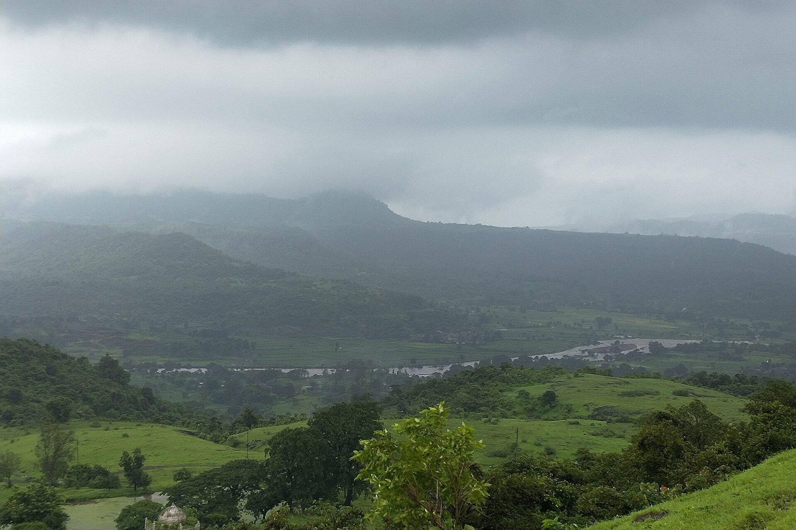 Green Western Ghats hills and a river valley under monsoon cloud near Pen in Raigad