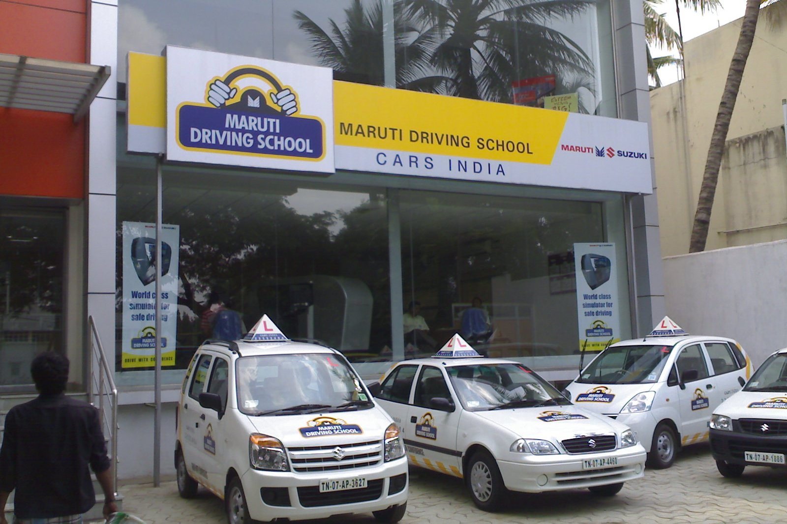White learner cars with L boards parked outside a Maruti Suzuki driving school branch
