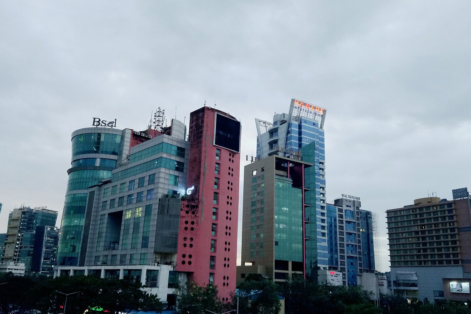 Glass and concrete commercial towers of different heights in Vashi under an overcast dusk sky