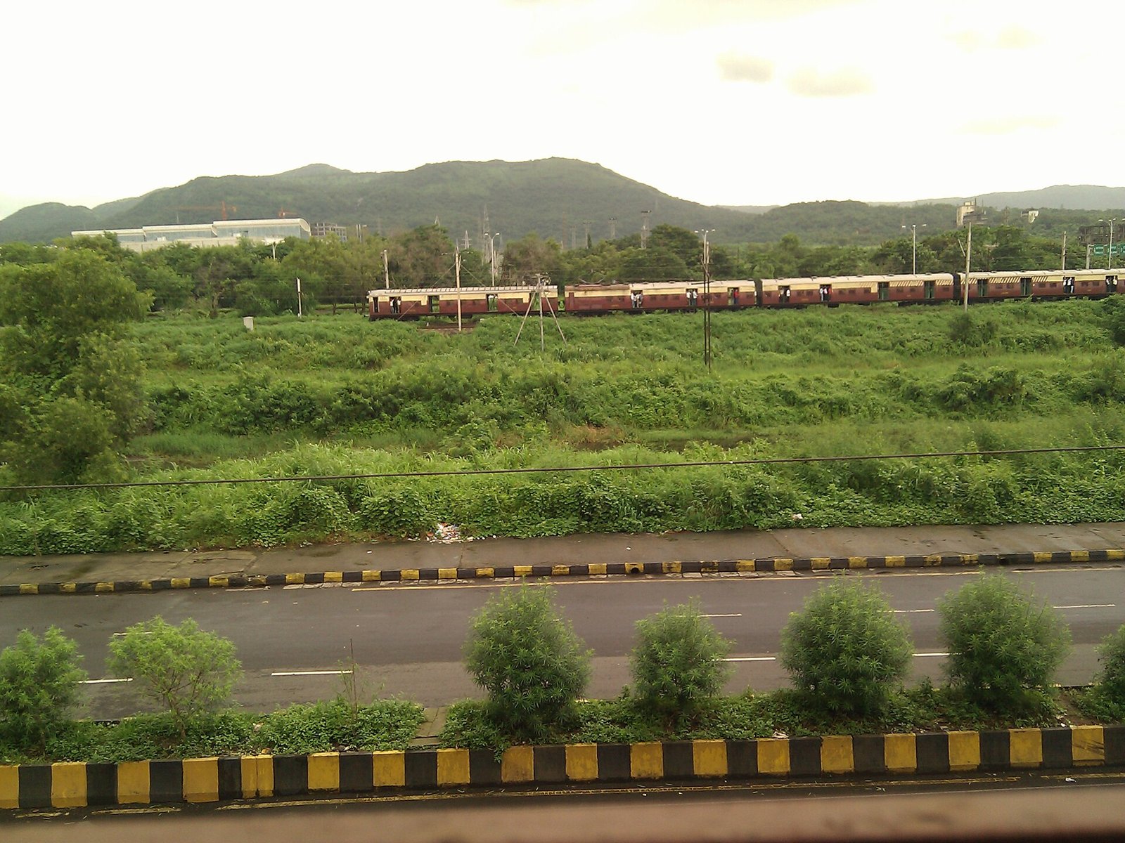 A local train running past green hills near Ghansoli