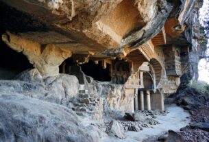 Weathered rock-cut Buddhist caves with carved facades in a cliff face near Karjat