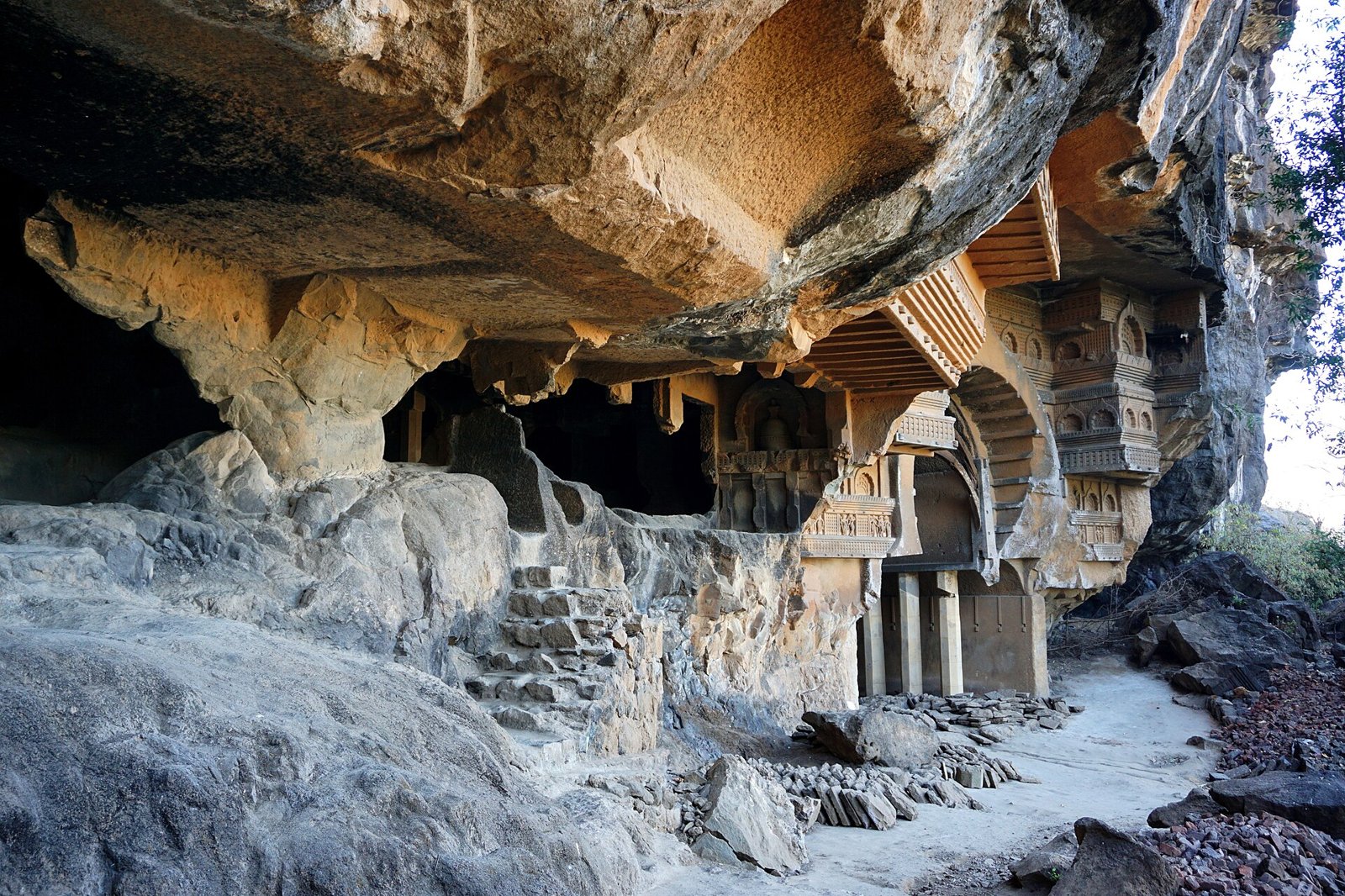 Weathered rock-cut Buddhist caves with carved facades in a cliff face near Karjat