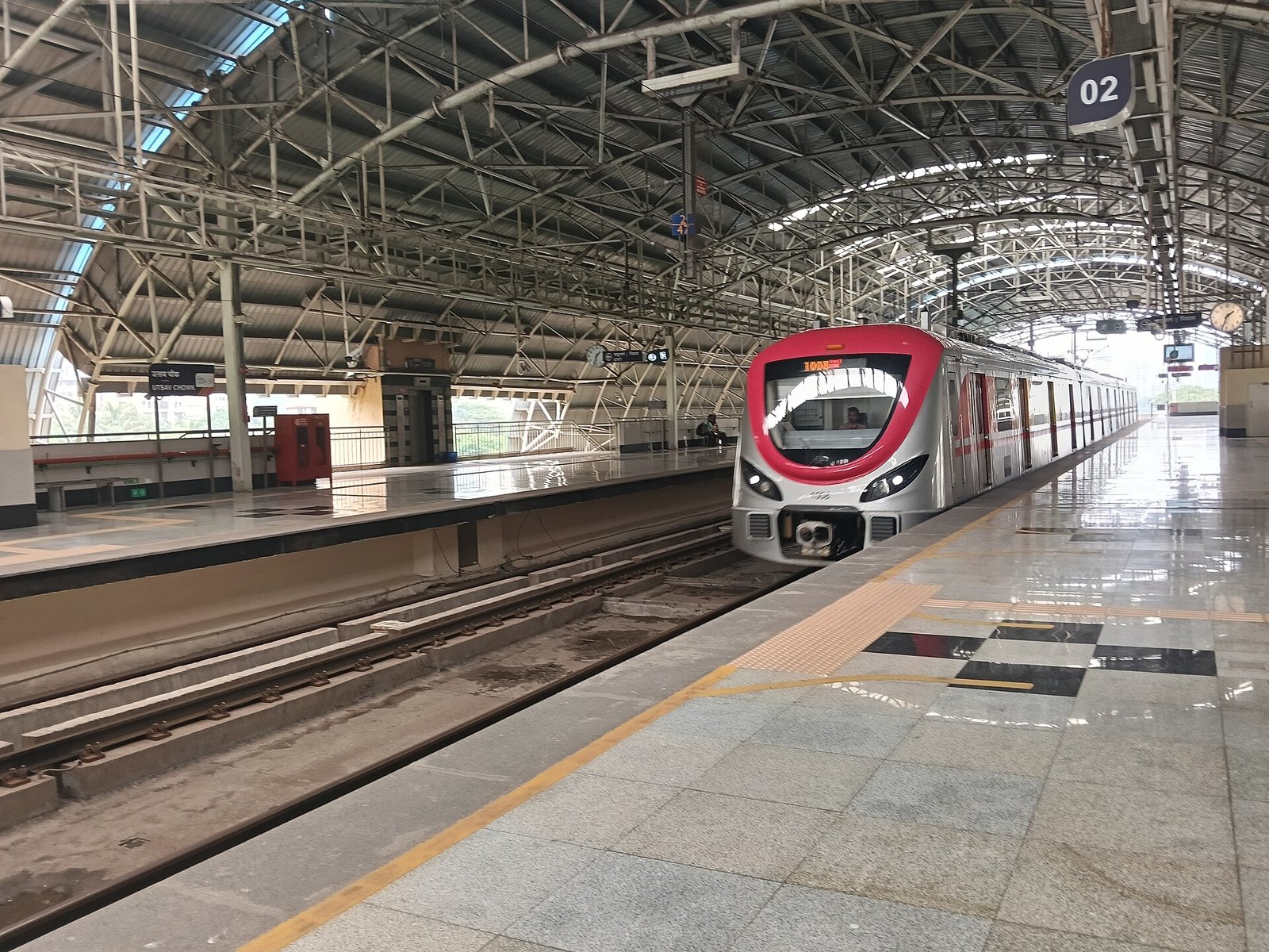A silver and red Navi Mumbai Metro Line 1 train at the platform of Utsav Chowk station in Kharghar