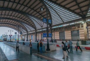 Passengers on the platform under the curved glass roof at Bamandongri railway station on the Port line