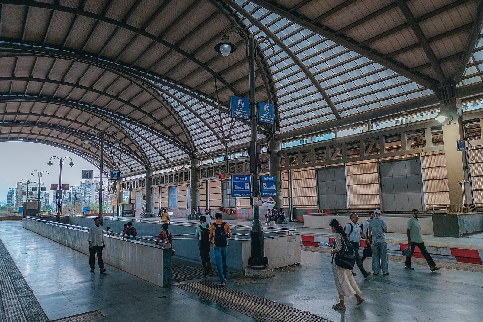 Passengers on the platform under the curved glass roof at Bamandongri railway station on the Port line