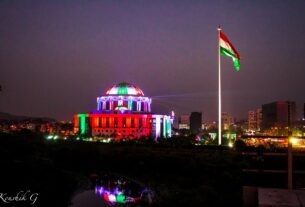 The Navi Mumbai Municipal Corporation building lit up in tricolour colours at night beside a tall national flag