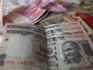 Indian 100 rupee and 2000 rupee notes with foreign currency notes and a passport