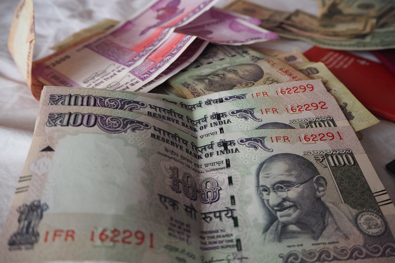Indian 100 rupee and 2000 rupee notes with foreign currency notes and a passport