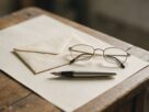 An envelope, reading glasses and a fountain pen on a blank sheet