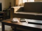 A living room with rent receipts, a calculator, a pen and a closed laptop on a coffee table