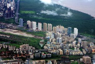 Aerial view of high-rise towers below a forested hill in Navi Mumbai