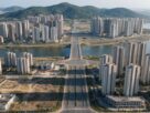 An AI generated aerial view of a planned coastal city with towers, a bridge and hills